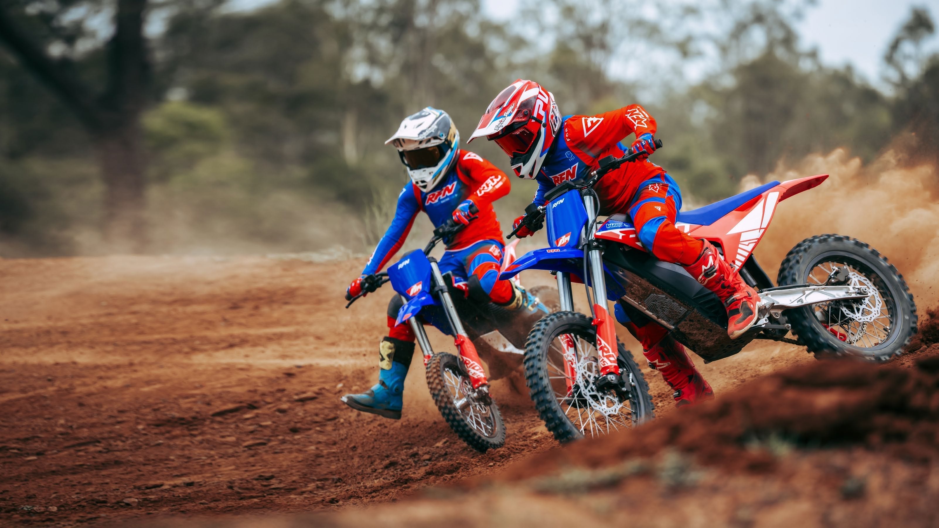 Two RFN riders cornering on red and blue electric dirt bikes